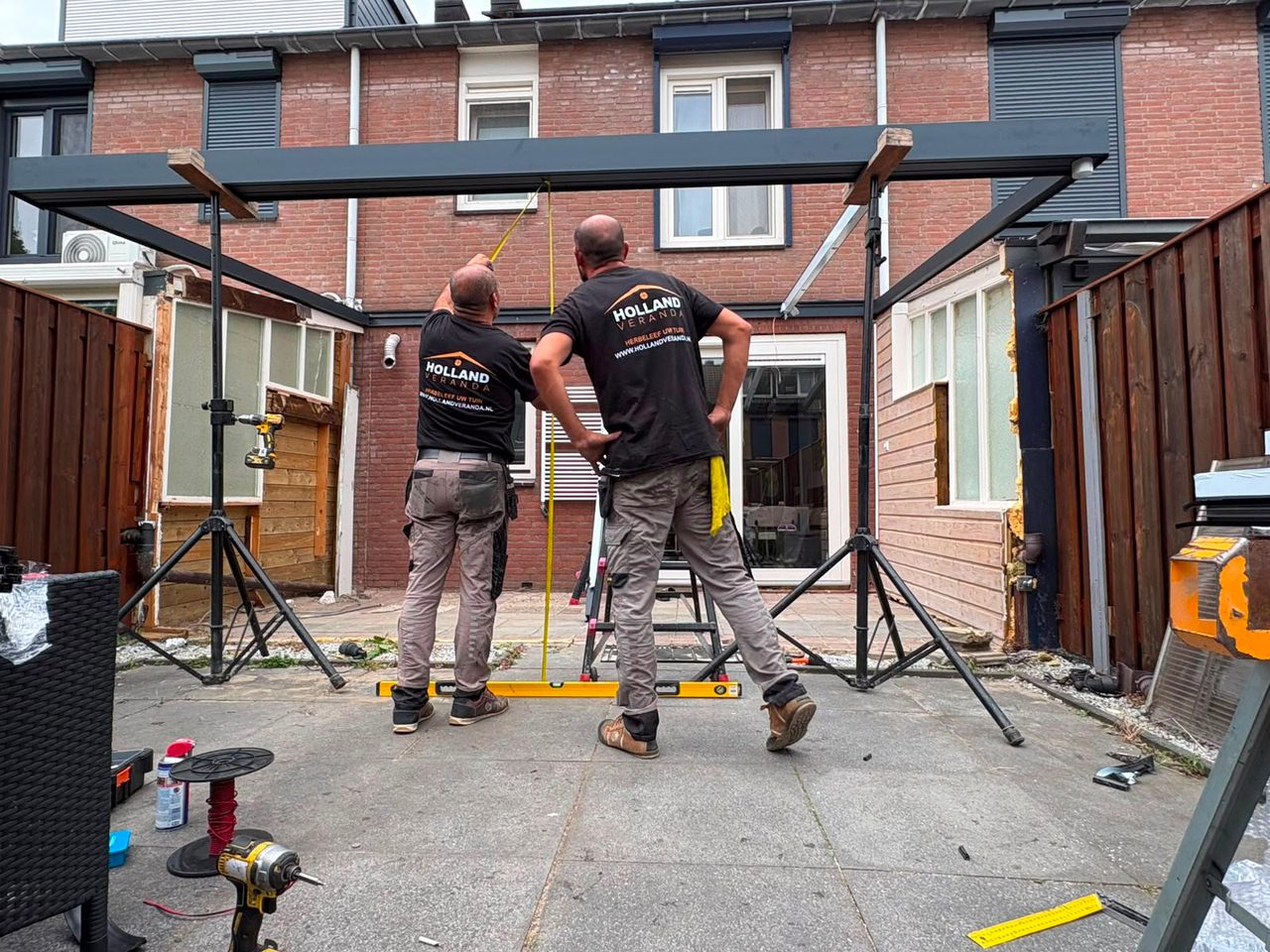 Zwei Monteure in Holland-Veranda-Shirts richten einen Rahmen mit der Wasserwaage aus