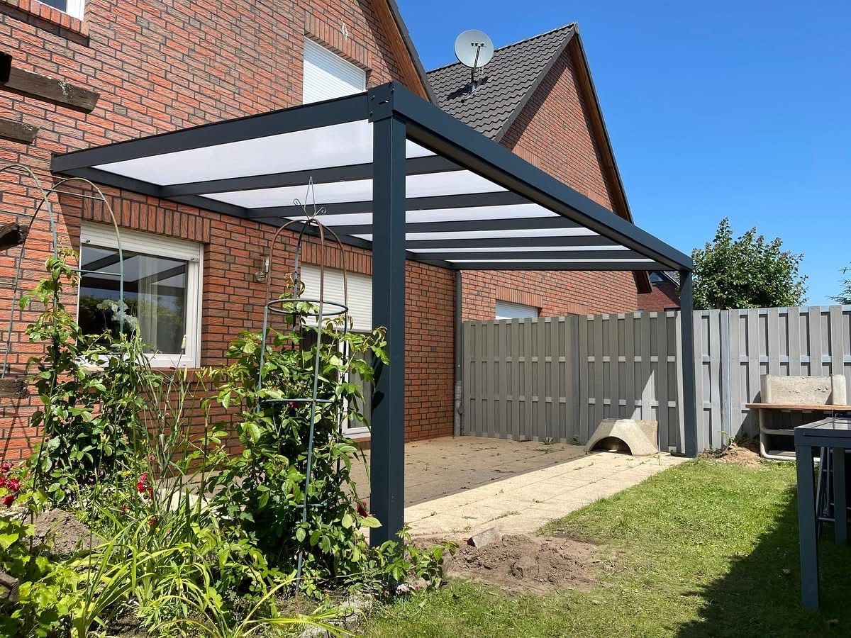 Kompakte Terrassenüberdachung mit opalem Dach an einer roten Backsteinfassade