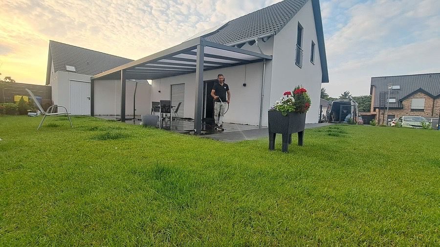 Überdachung an einem weißen Haus mit großer Rasenfläche im Abendlicht