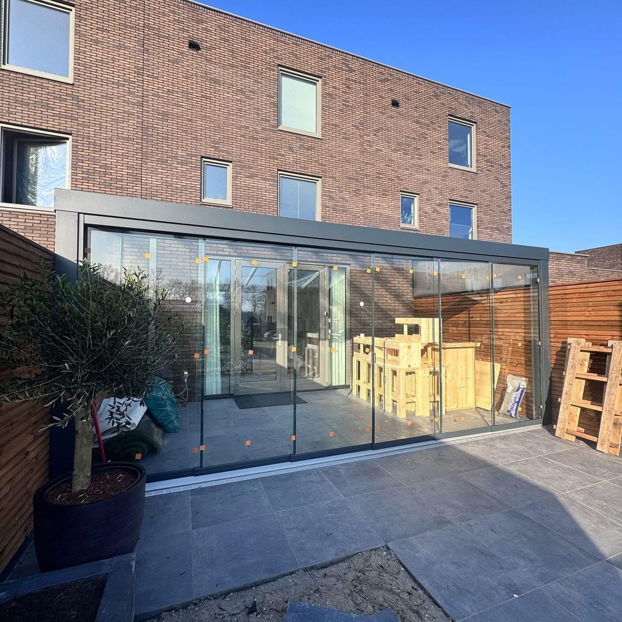 Sommergarten mit Glasschiebewänden an einem Backsteinreihenhaus