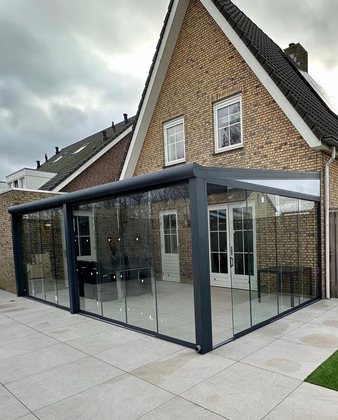 Ecksommergarten mit Glasschiebewänden an einem gelben Backsteinhaus