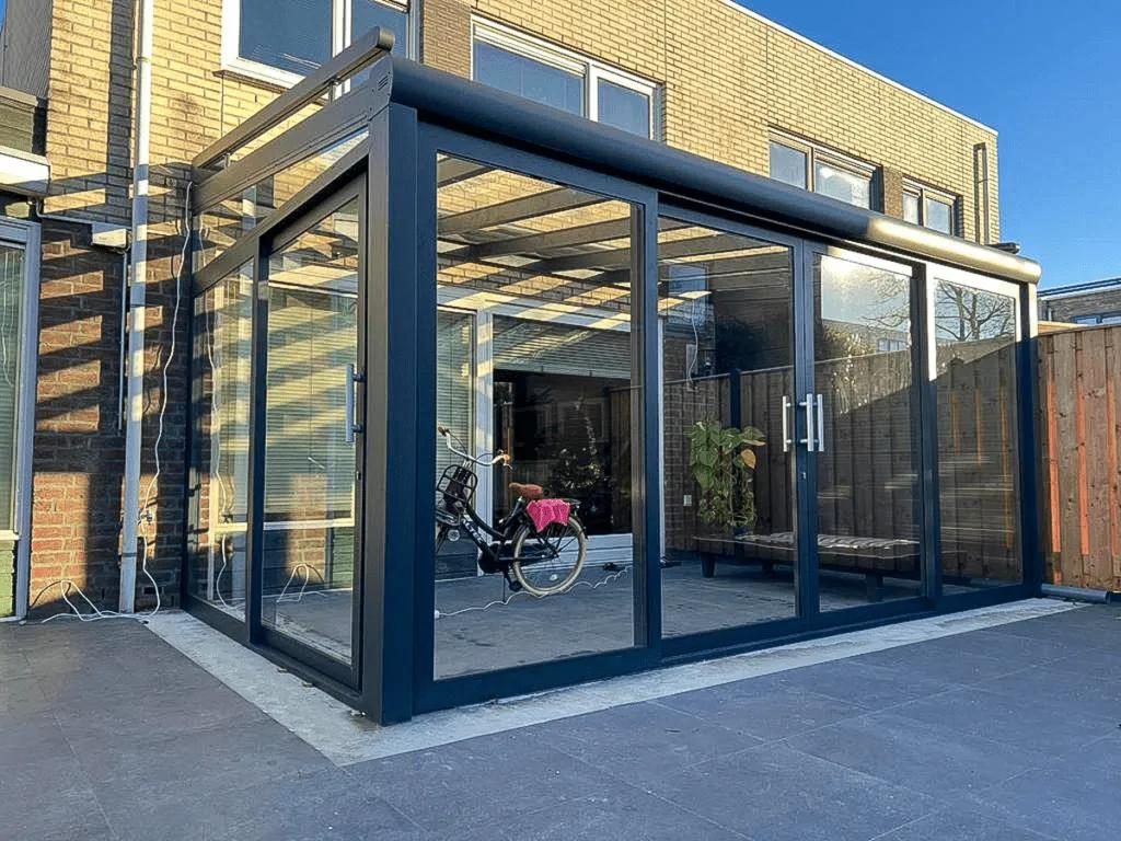 Sommergarten mit Glasschiebewänden an einem gelben Backsteinhaus