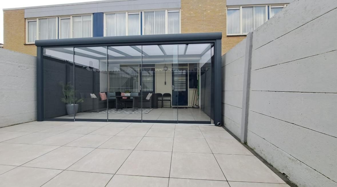 Sommergarten mit Glasschiebewänden in einem gepflasterten Stadtgarten